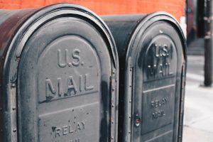 A closeup of the rounded tops of two mail boxes that say U.S. mail. These are relay boxes so they're not the typical blue. They are bronze colored